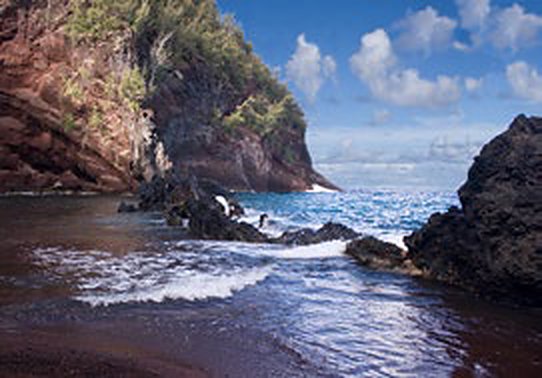 Red sand cove with dark lava rocks near Hana
